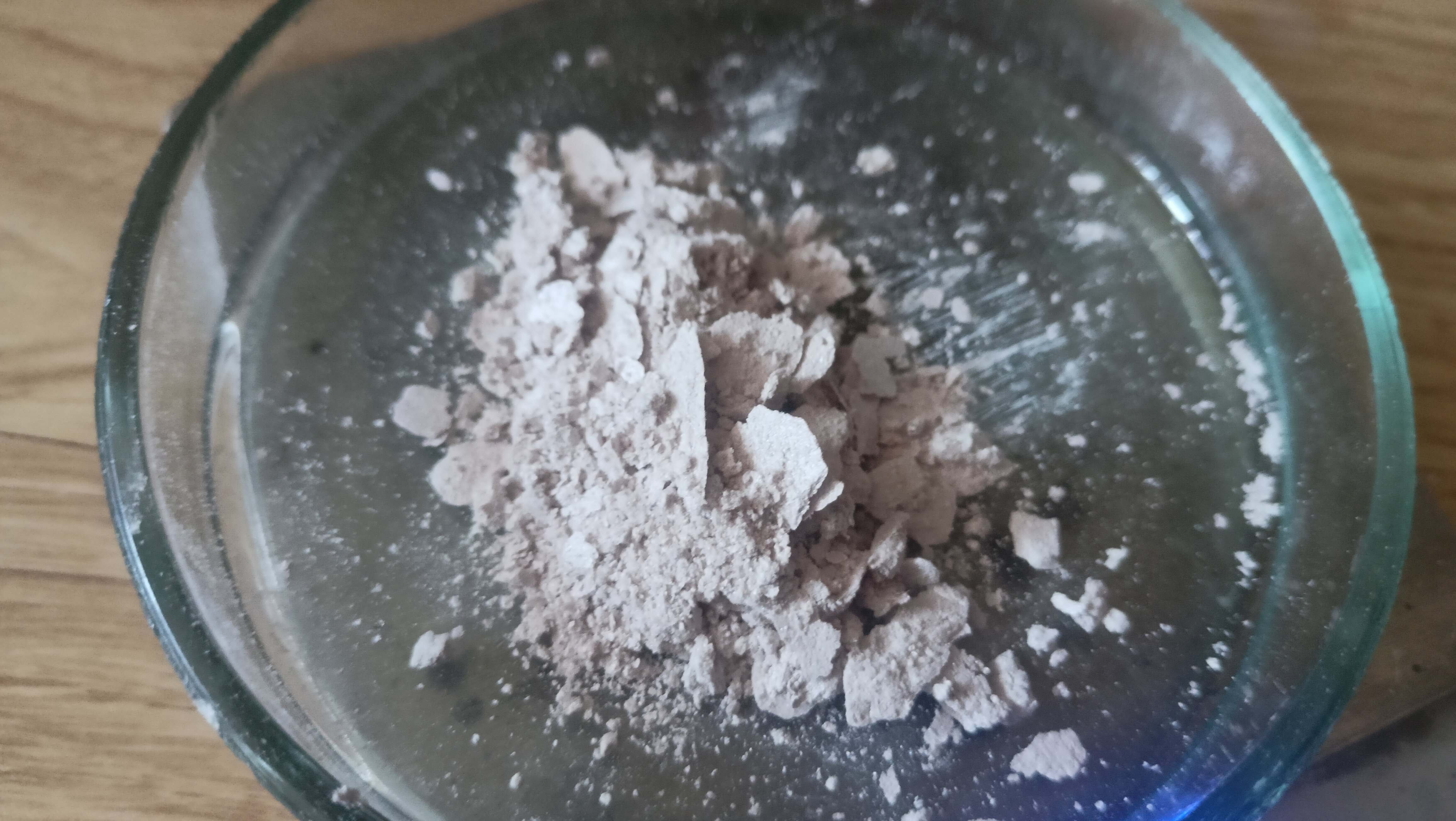 flakey beige-pink-grey powder in a petri dish